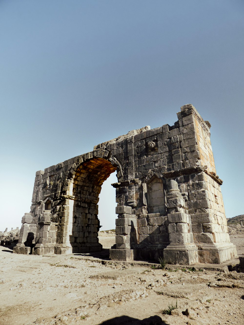 a stone structure with a door in the middle of a desert