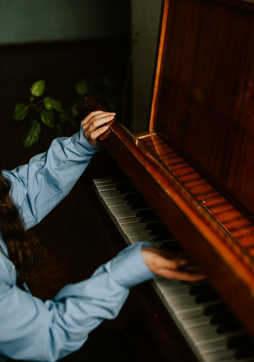 a woman in a blue shirt is playing a piano