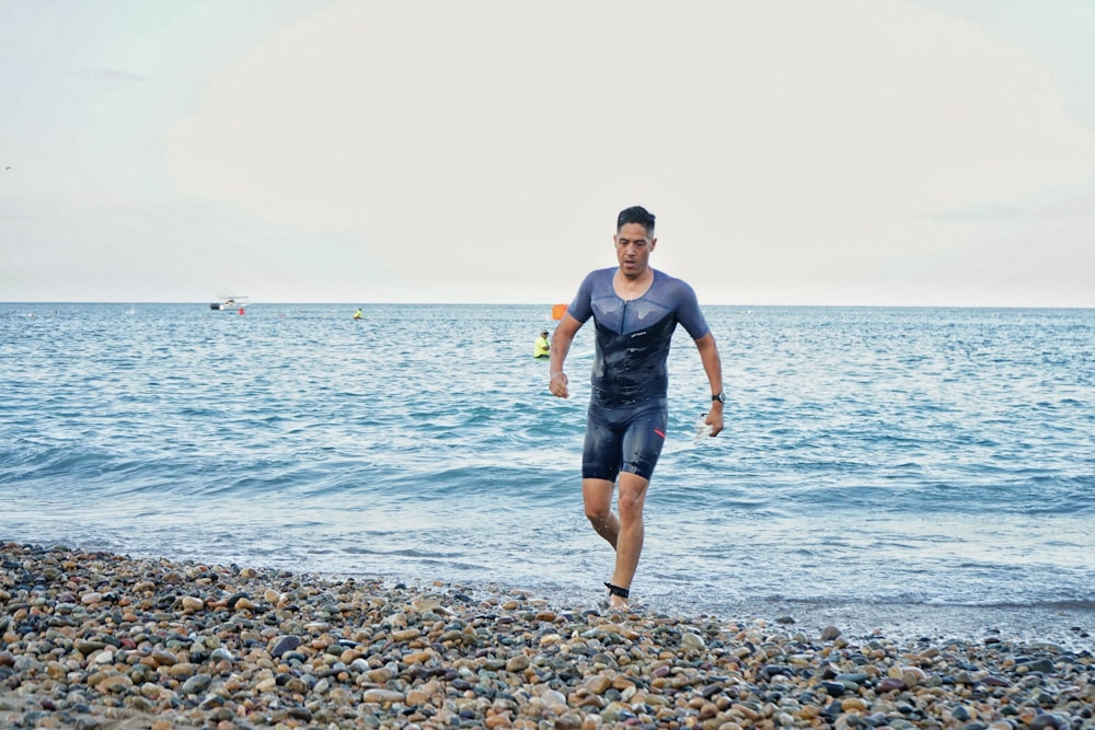 a man is running on the beach near the water
