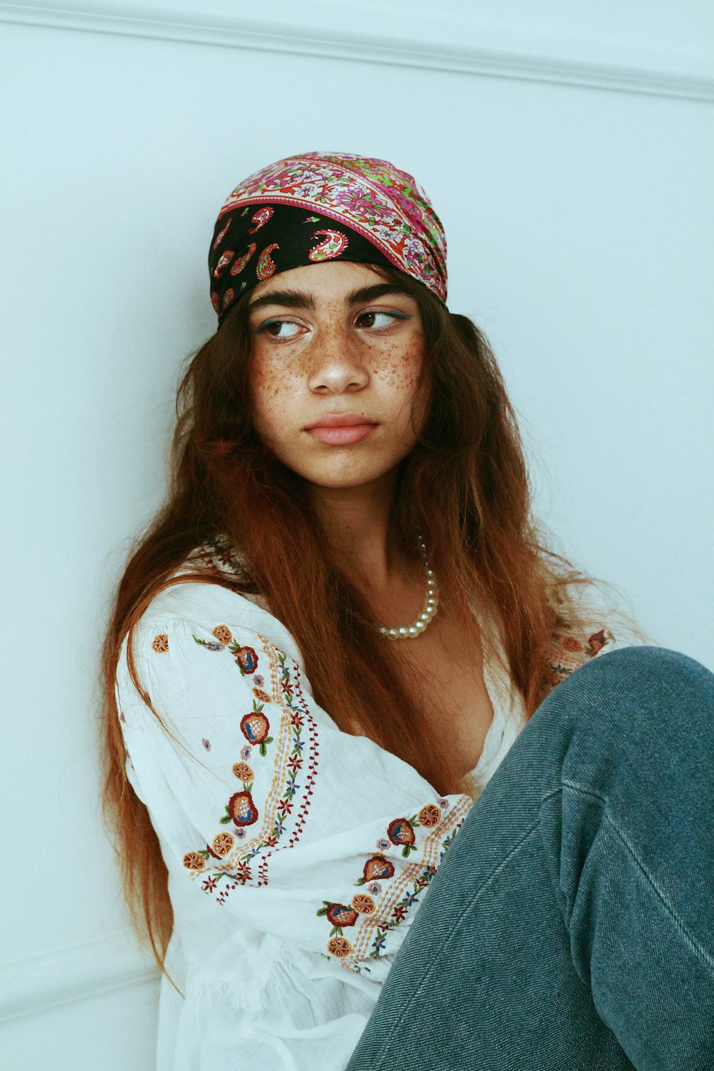 a woman with freckles and a hat sitting on the floor