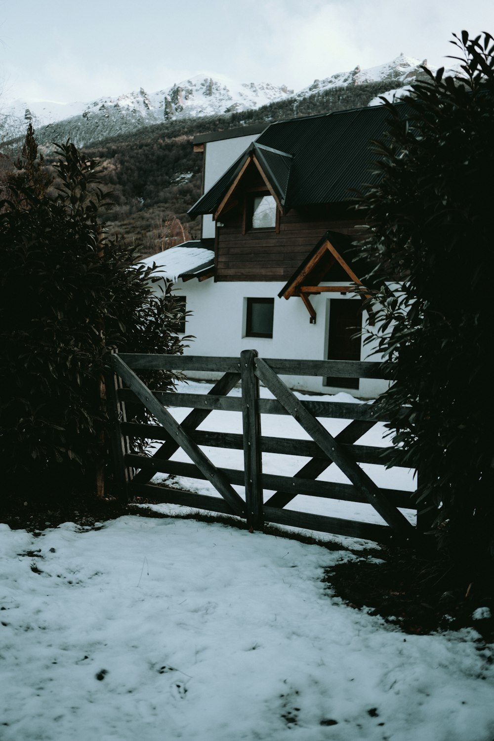 a white house with a wooden fence in the snow