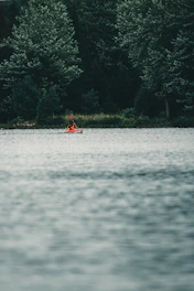 A kayaker paddling gently along a calm river surrounded by tropical trees.