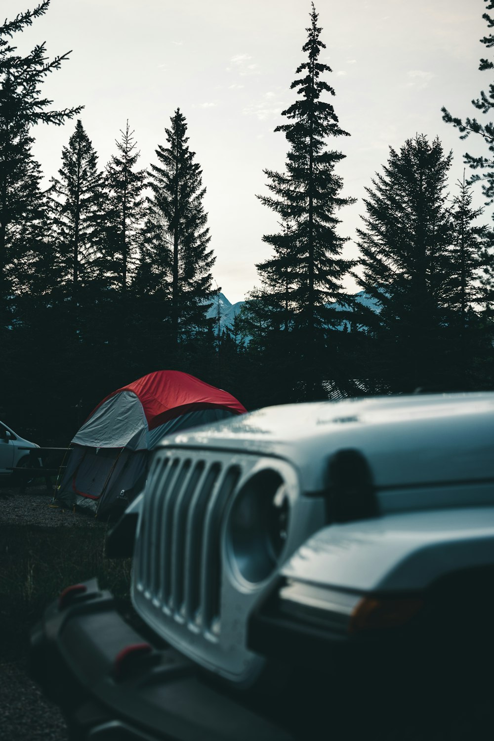 a jeep parked next to a tent in the woods