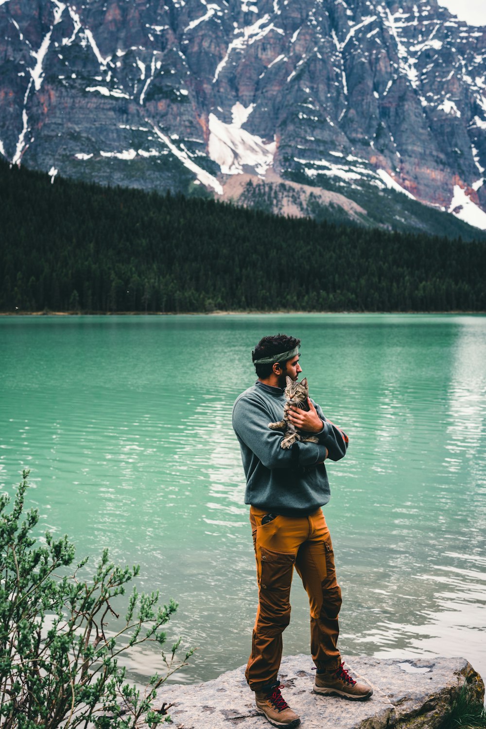 a man standing on a rock next to a lake