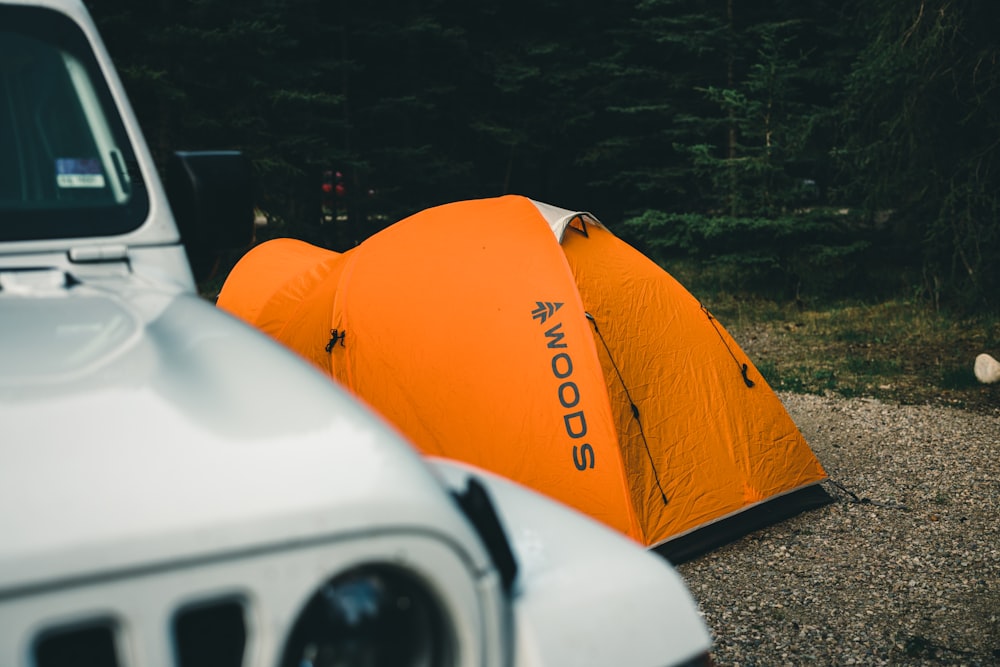an orange tent sitting next to a white jeep
