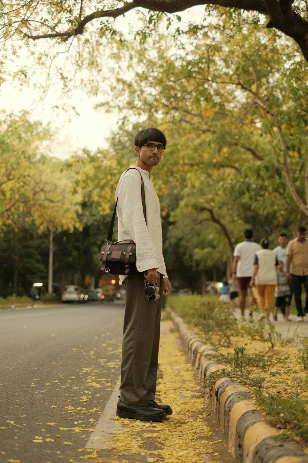 a man standing on the side of a road holding a camera