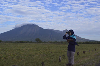 A detective taking notes while observing a scene through binoculars.