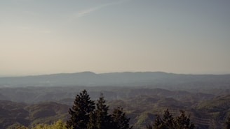 A peaceful morning scene with dewy grass and distant mountains visible beyond the farmhouse.