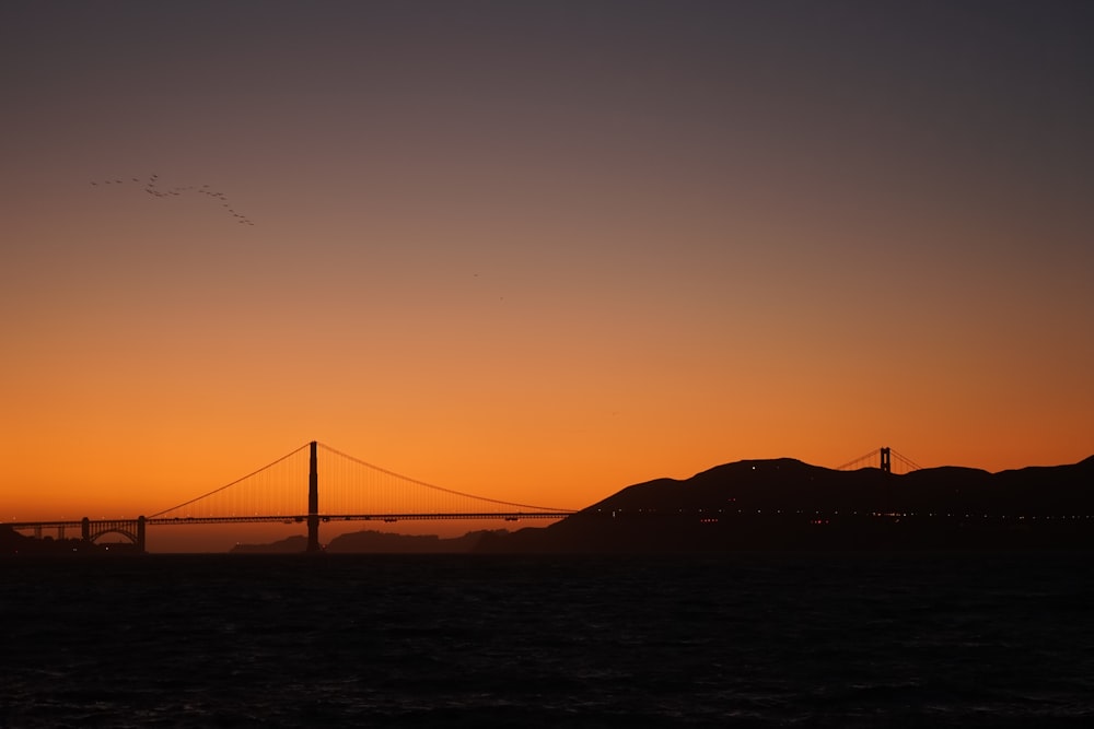 the golden gate bridge is silhouetted against a sunset