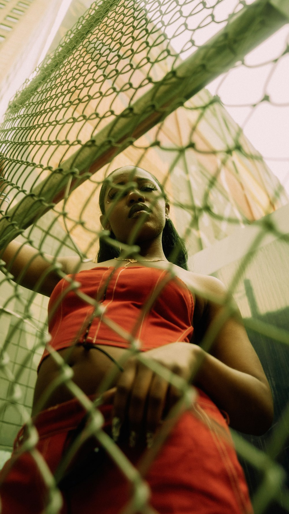 a woman in a red shirt leaning against a net