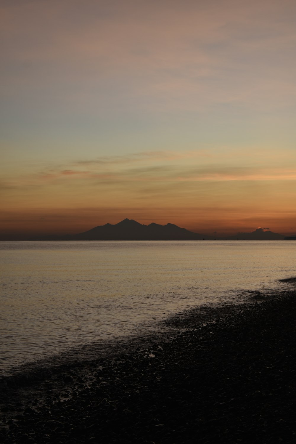 the sun is setting over the ocean and mountains