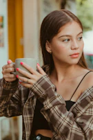 A stylish young woman wearing a pop icon inspired cap and holding a music-themed mug.