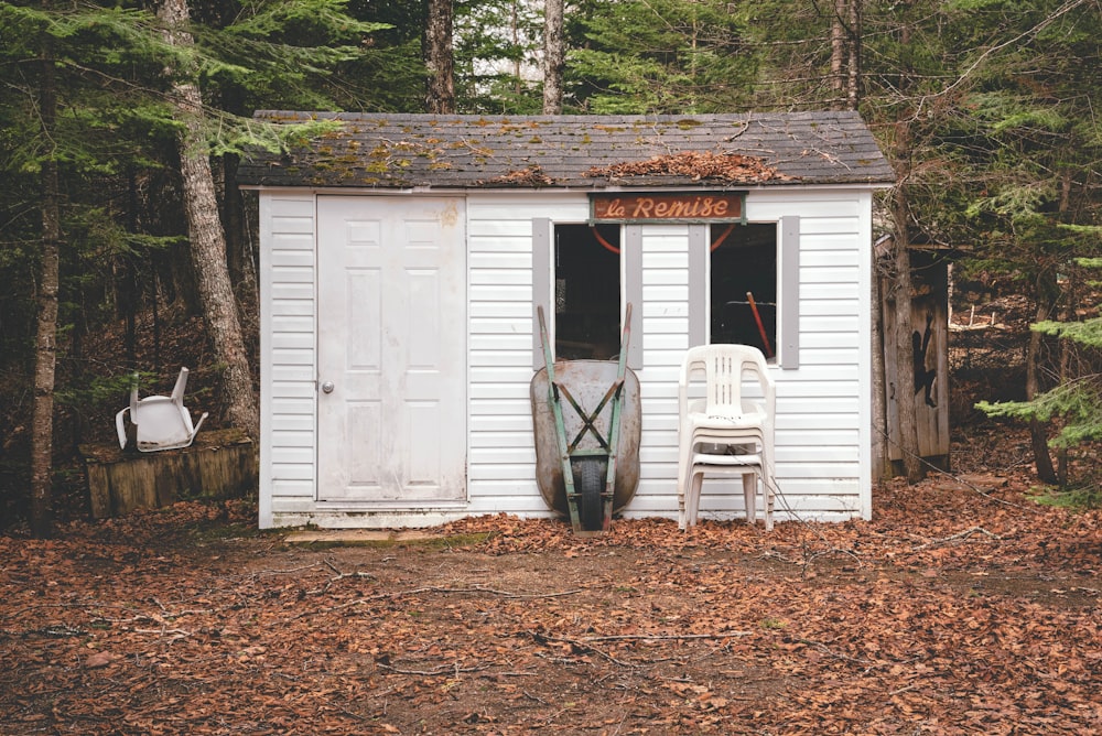 a white shed with a chair and a surfboard