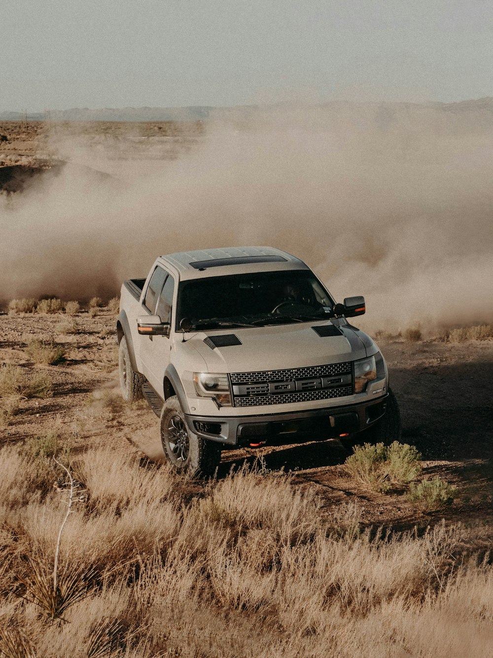 a white truck driving down a dirt road