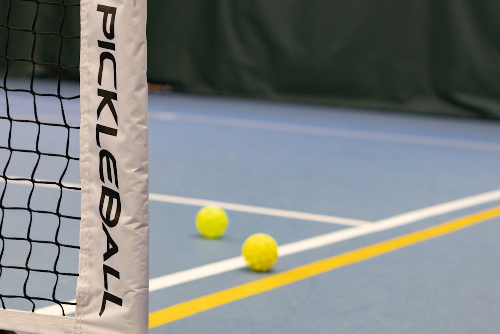 three tennis balls on a tennis court near a net