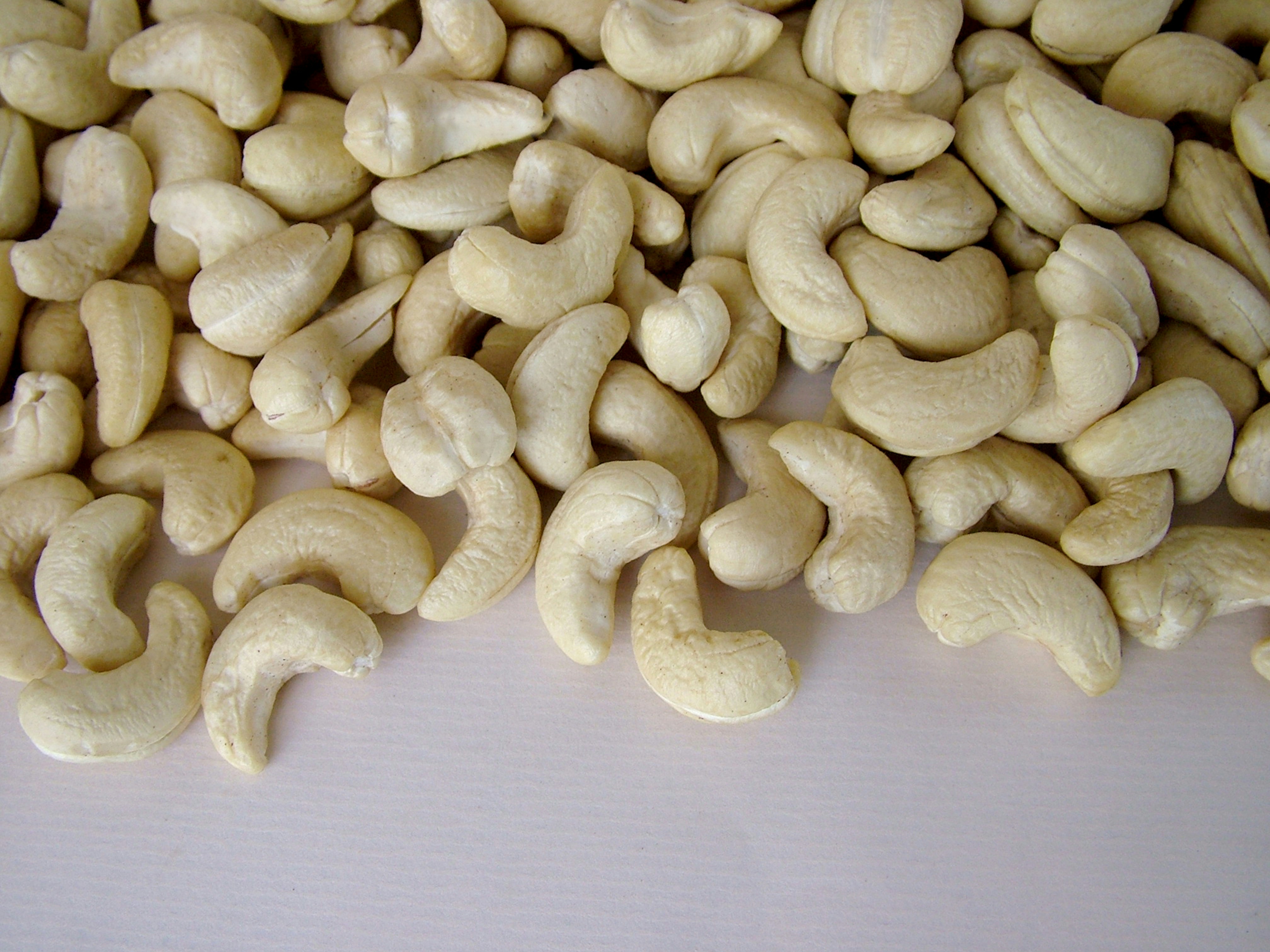 Creamy white cashew nuts in a wooden bowl under bright natural daylight