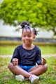 a little girl sitting in the grass with her hair in a bun