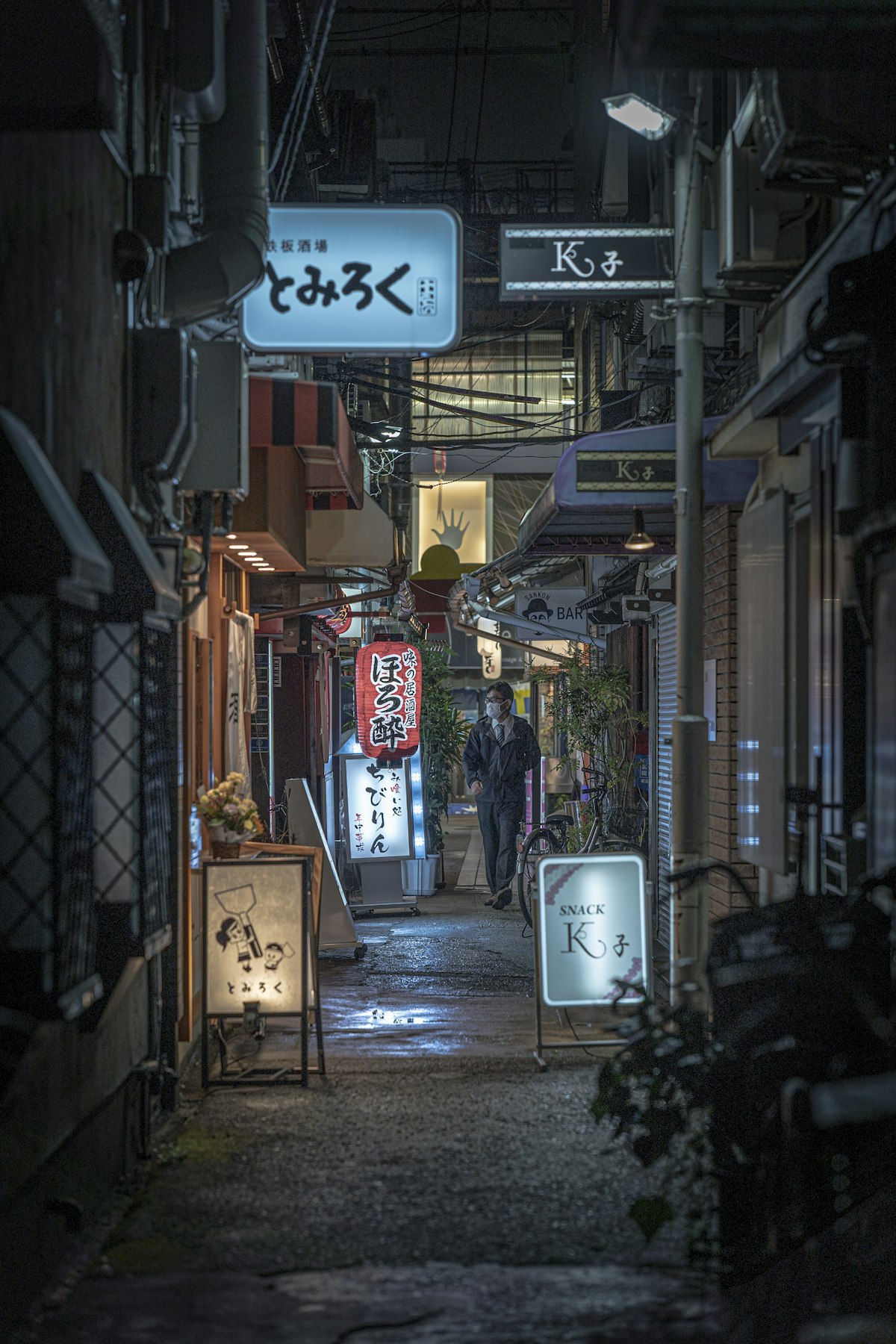 Narrow Osaka alley at night with small shops and Japanese signage