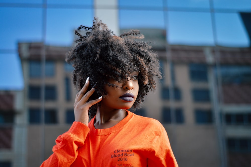 a woman in an orange shirt talking on a cell phone