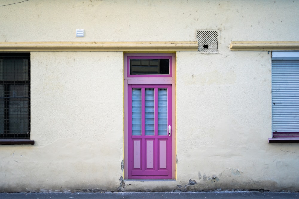 a pink and purple door on a white building