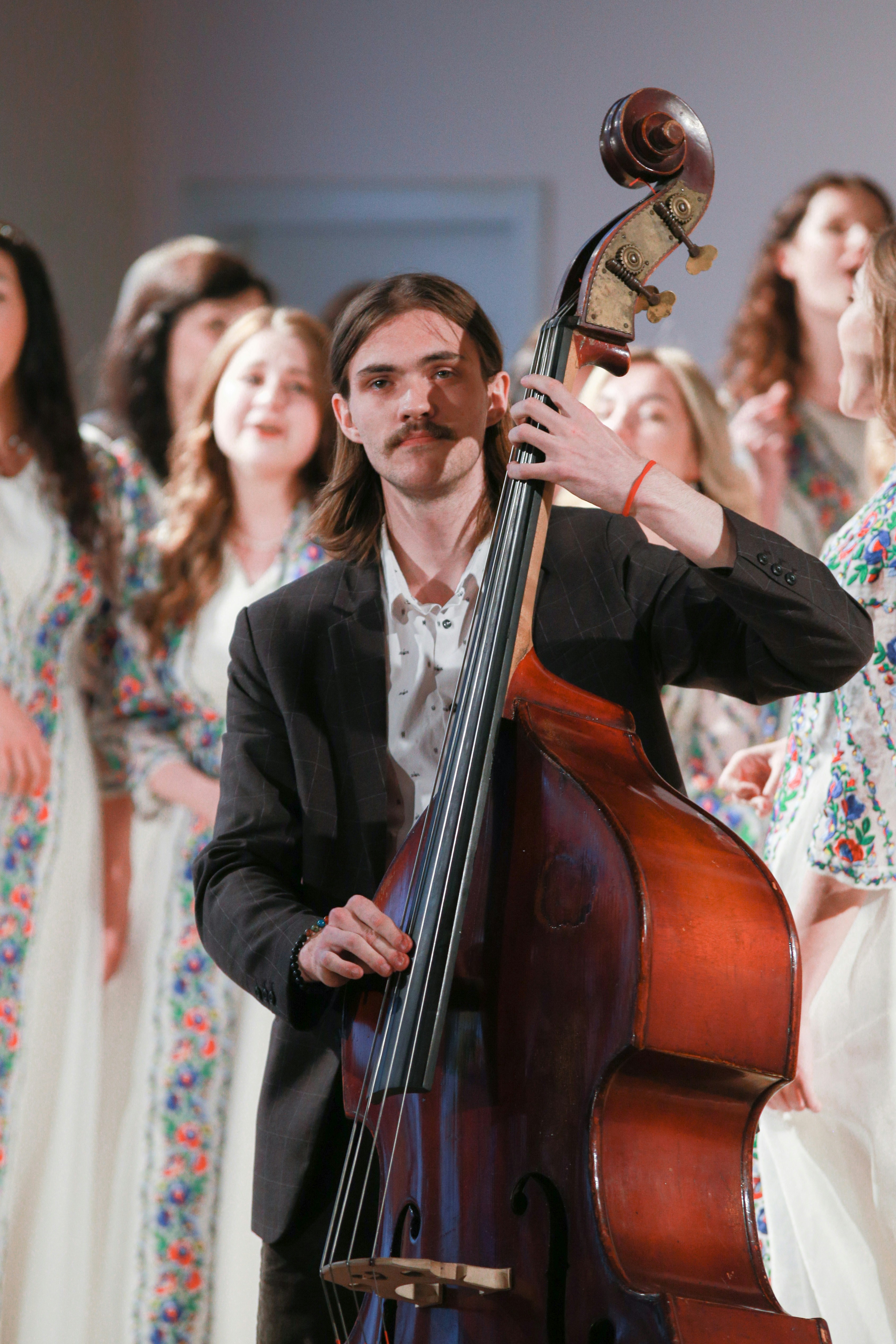 Un homme tenant un violoncelle devant un groupe de femmes