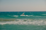 A windsurfer gliding swiftly over choppy blue waves under a clear sky.