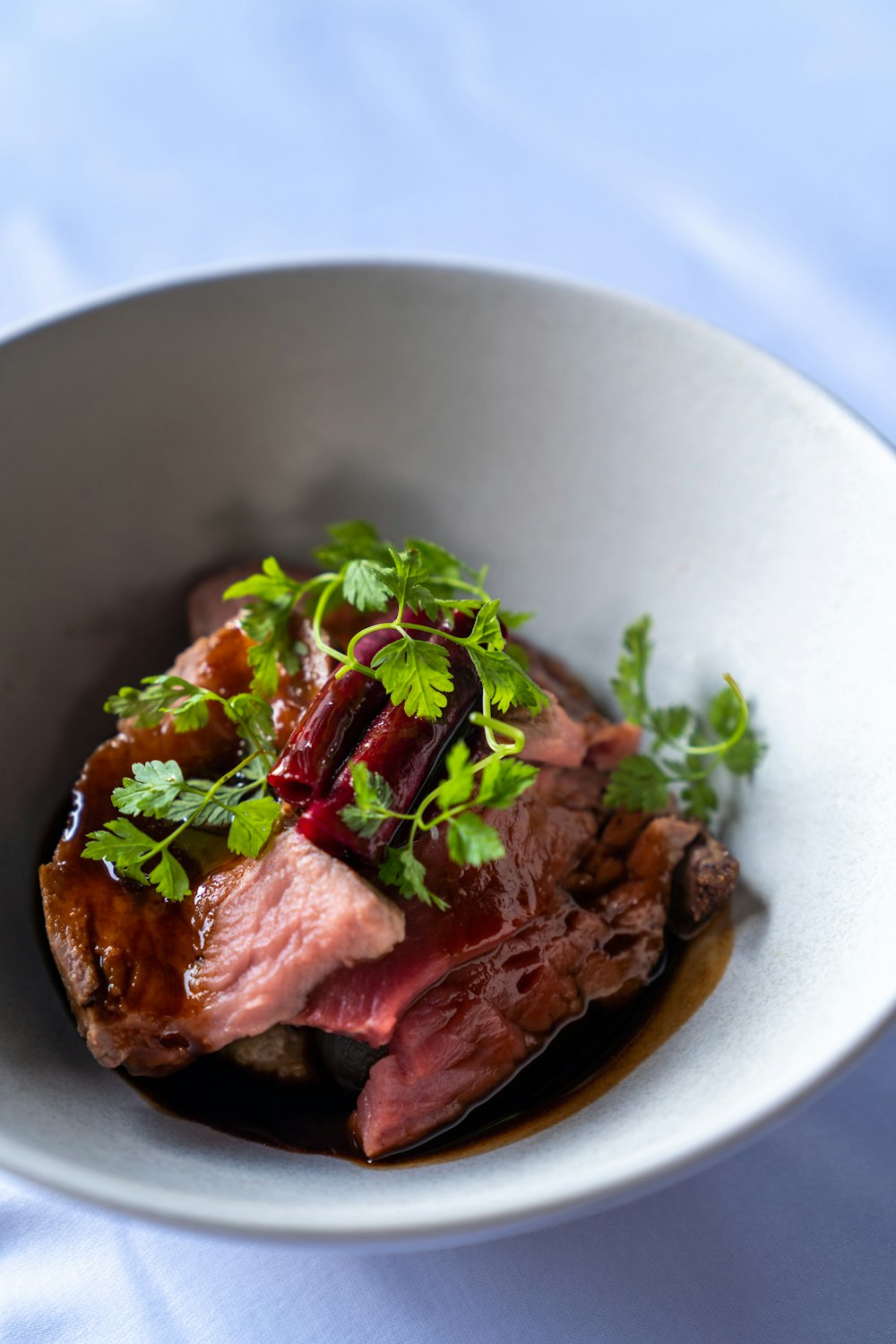 a white bowl filled with meat and vegetables