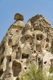 Guests exploring ancient cave dwellings carved into soft stone under a clear blue sky.