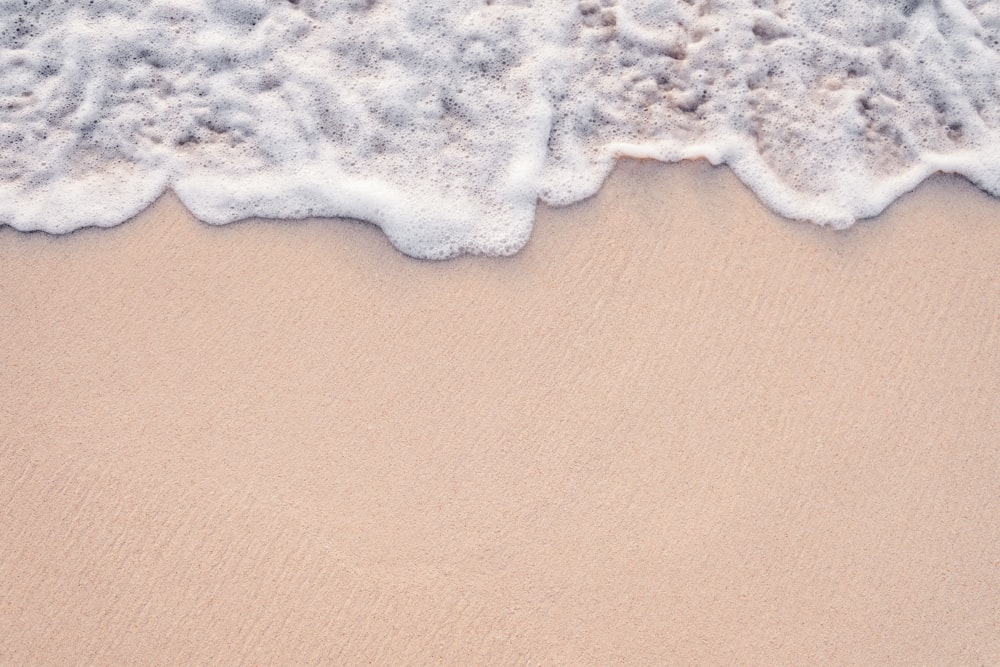 a sandy beach with a wave coming in to shore