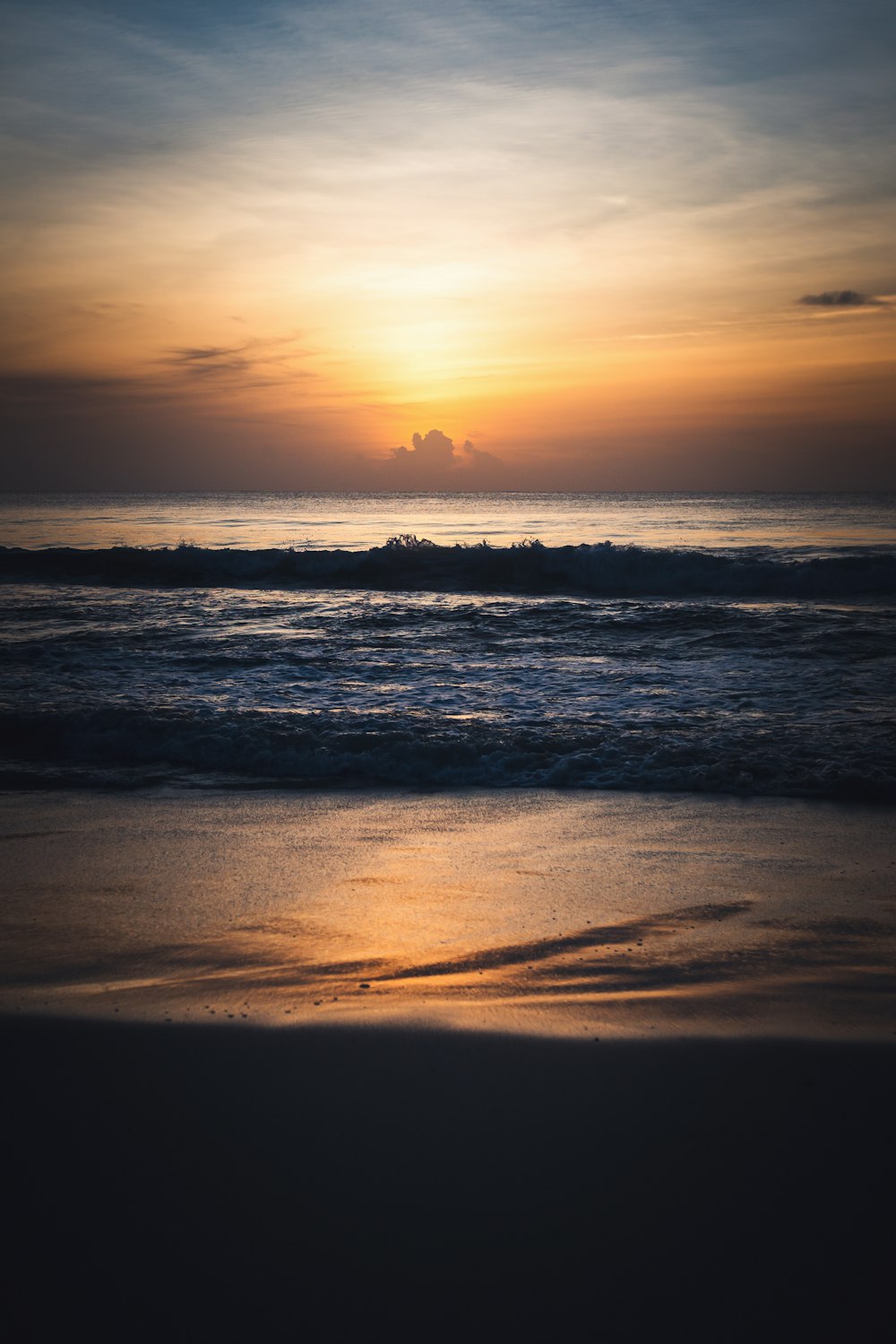 the sun is setting over the ocean on the beach