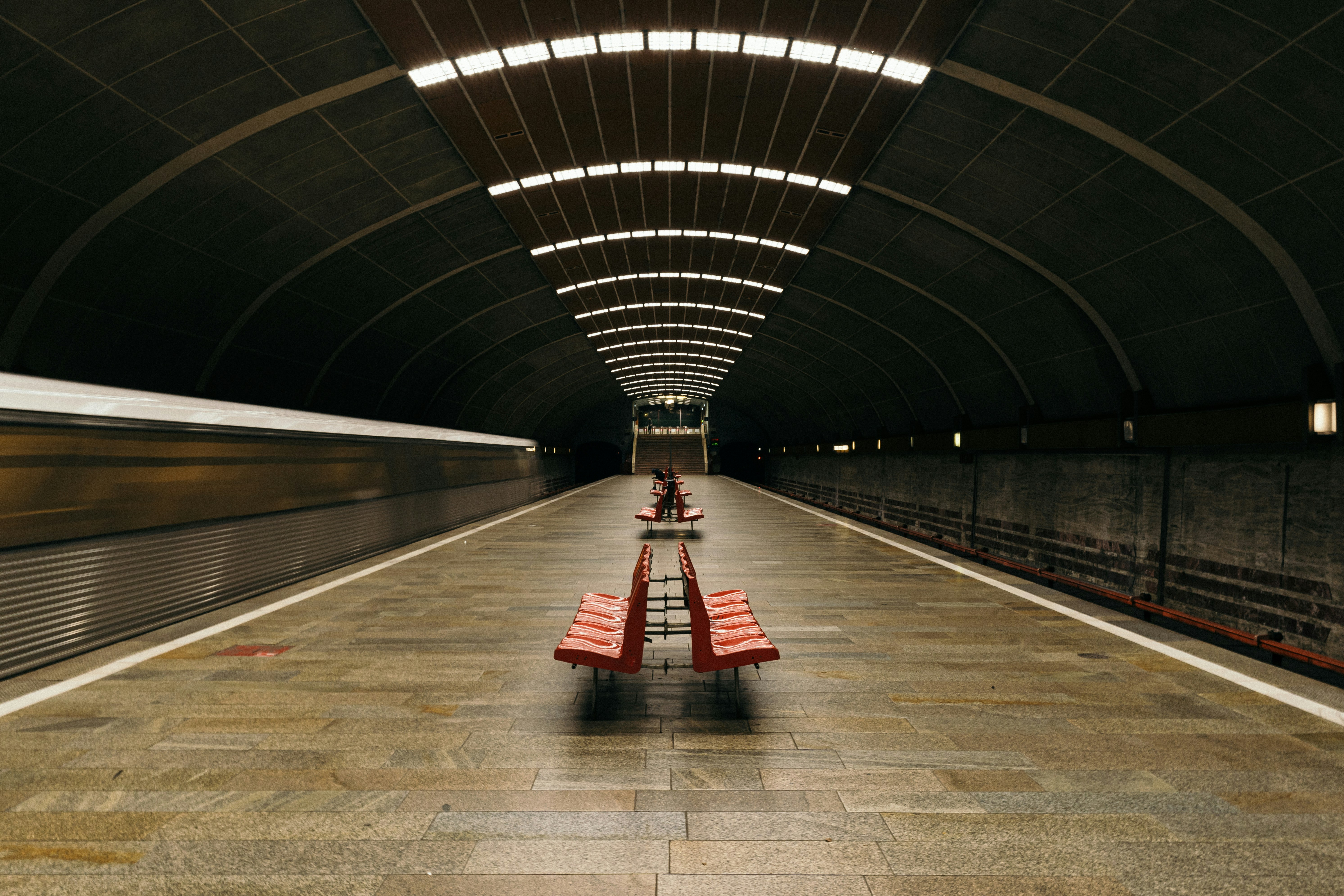 a train passing by a bench in a train station, 