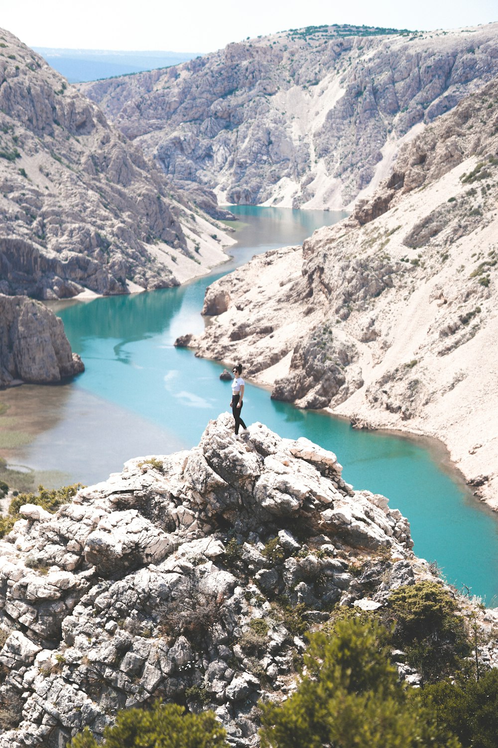 a person standing on top of a mountain next to a river