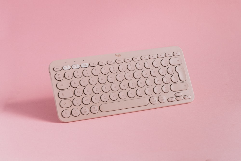 a computer keyboard on a pink background