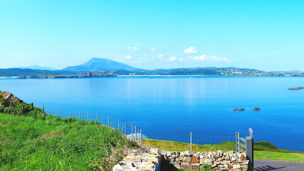 a large body of water sitting next to a lush green hillside