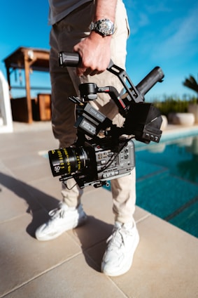 a man standing next to a pool holding a camera