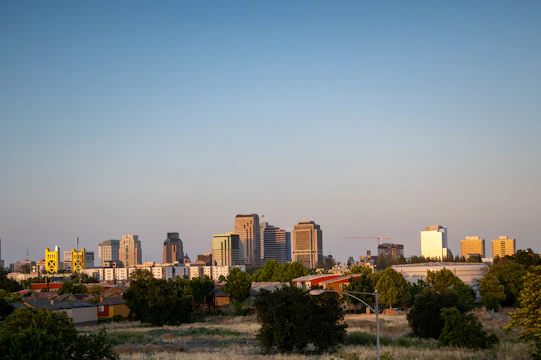 Gurgaon city skyline at sunset with illuminated high-rise buildings and soft golden light.