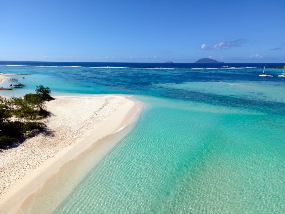 an aerial view of a beach with clear blue water