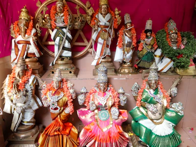 A vibrant display of traditional Mahalakshmi faces with pearl and kundan embellishments arranged on a wooden shelf.