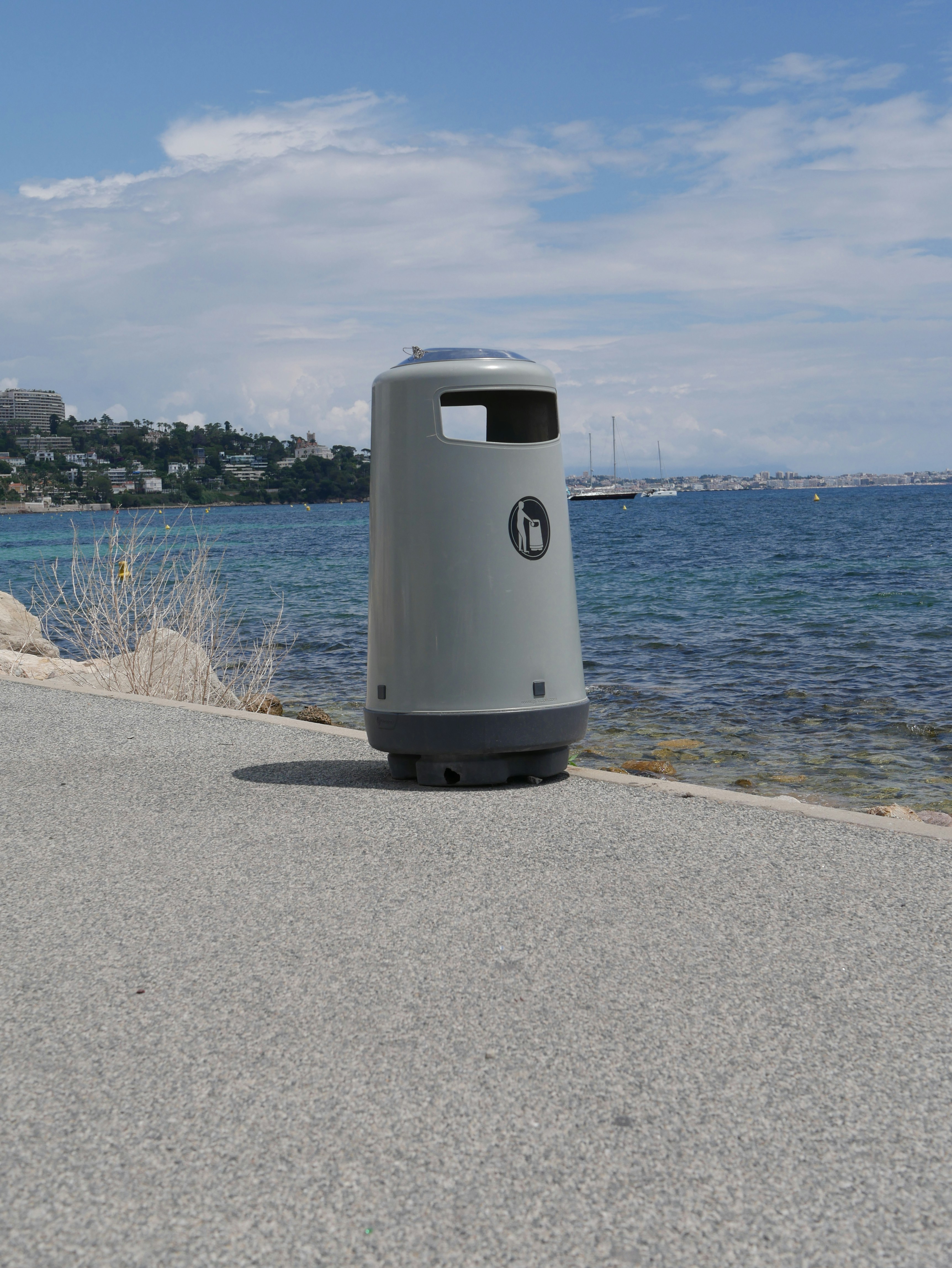 a gray trash can sitting on the side of a road
