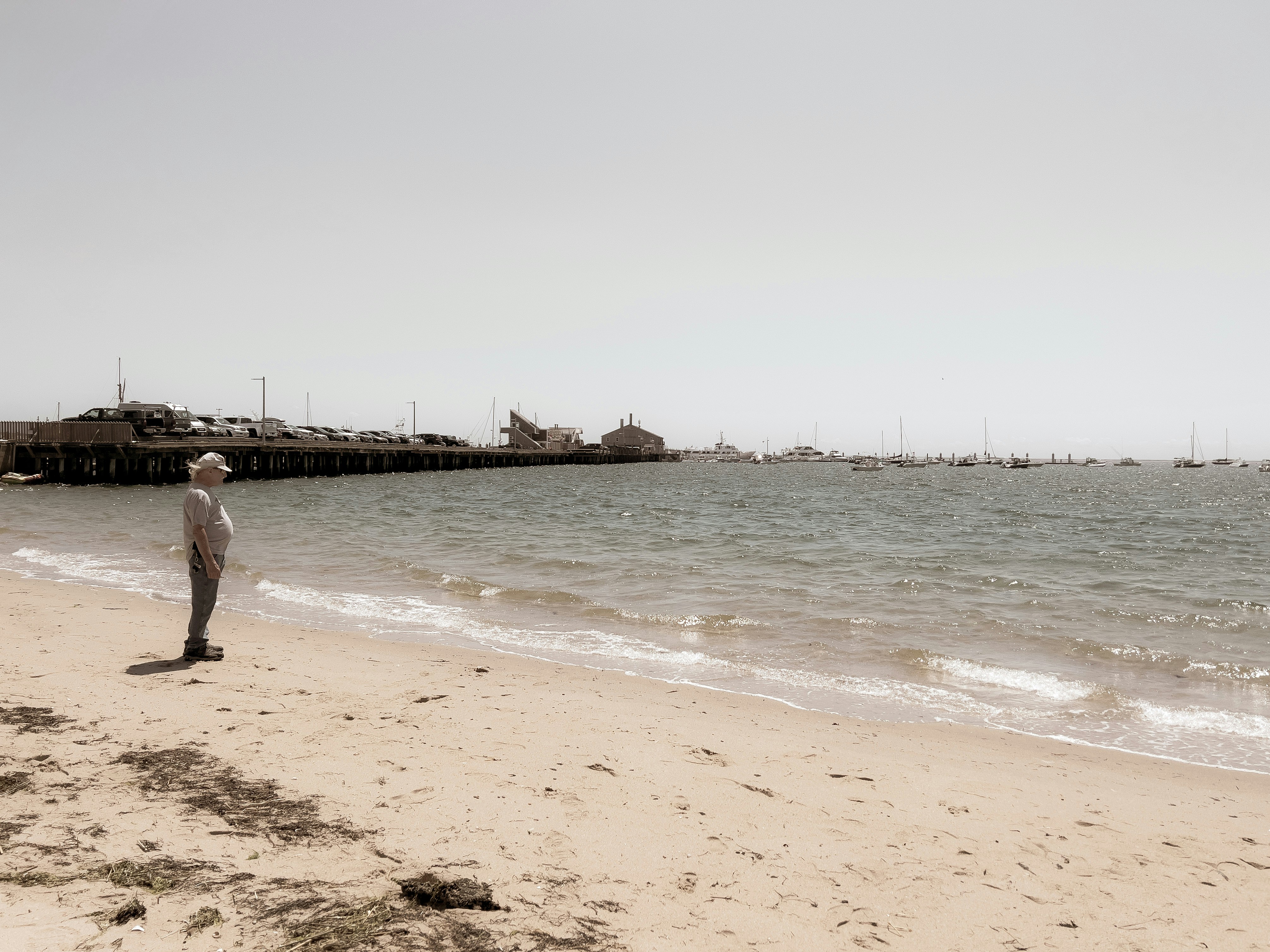 A man standing on top of a sandy beach next to the ocean photo – Free ...