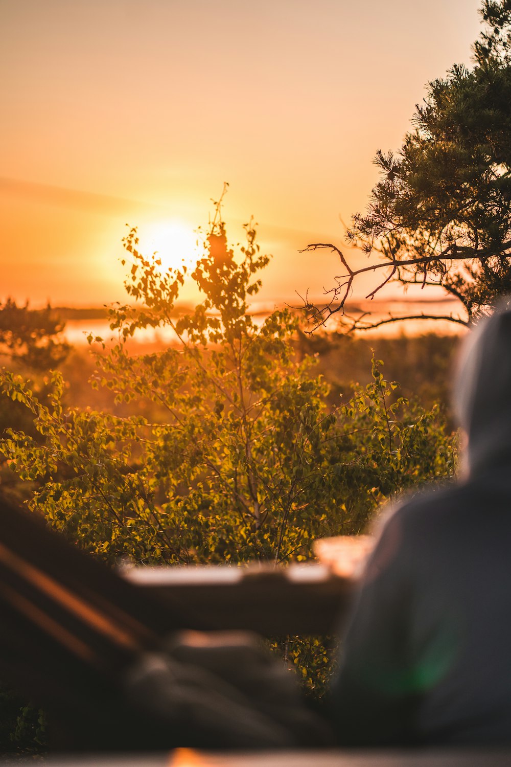 une personne assise dans un hamac regardant le coucher du soleil