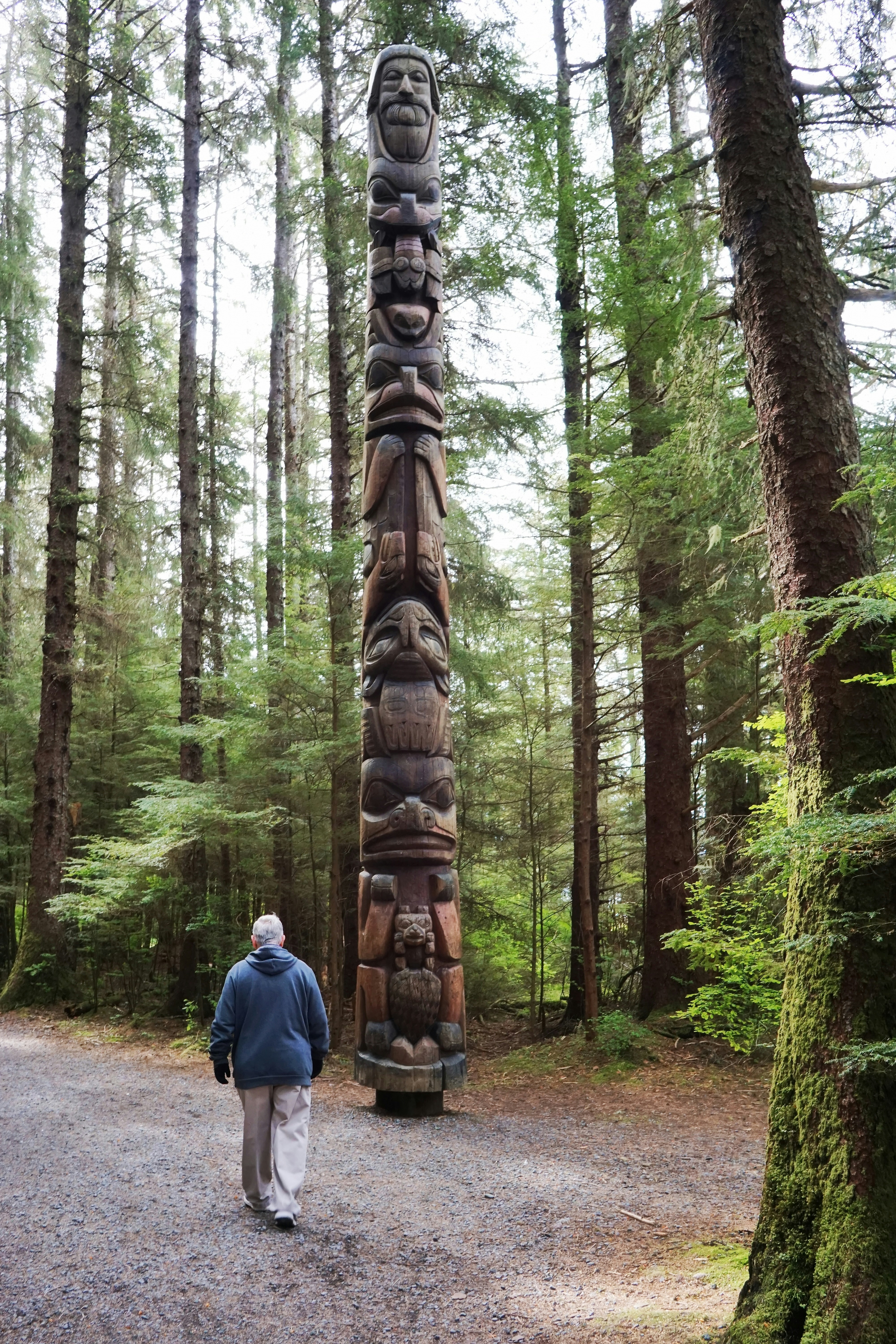 a man walking past a totem in a forest