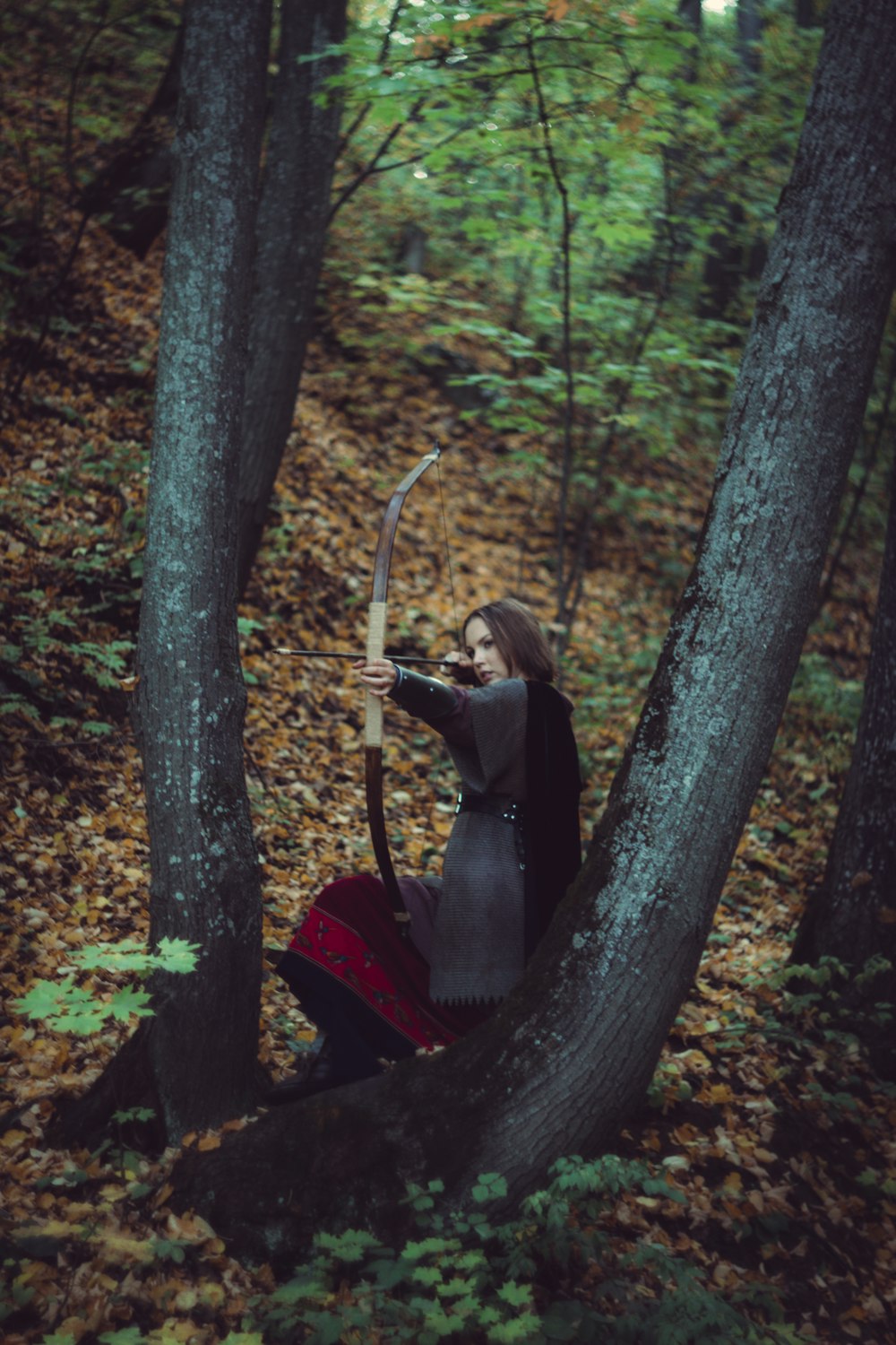 a woman with a bow and arrow in the woods