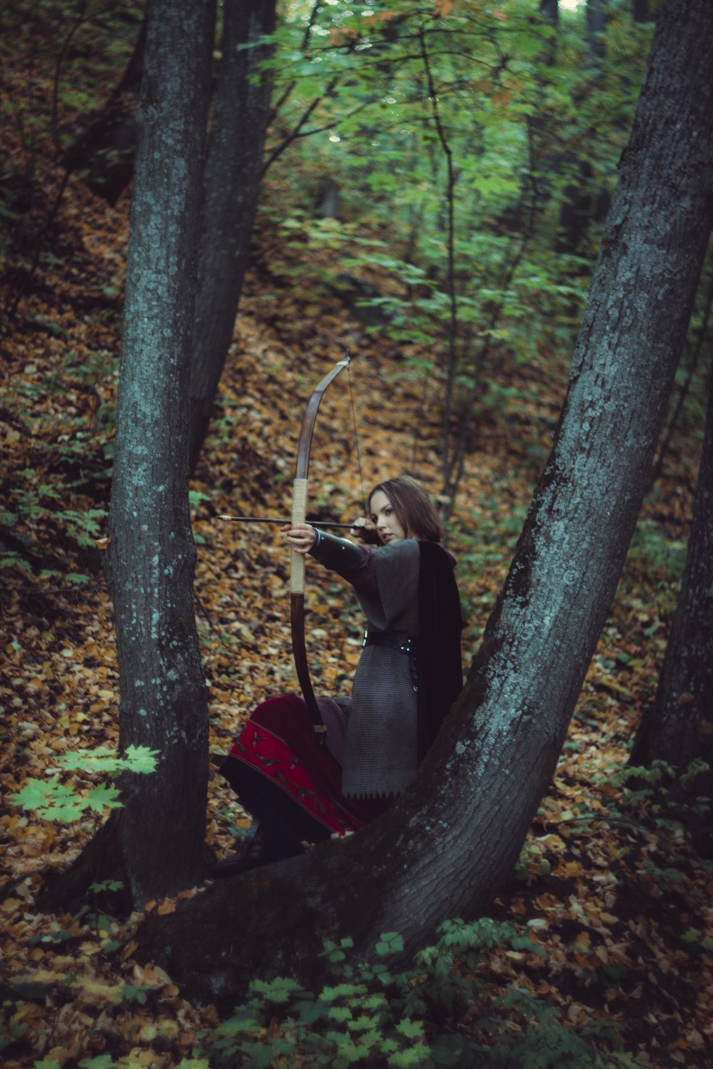 Una mujer con arco y flecha en el bosque