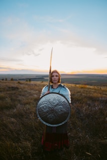 a woman holding a sword and shield in a field