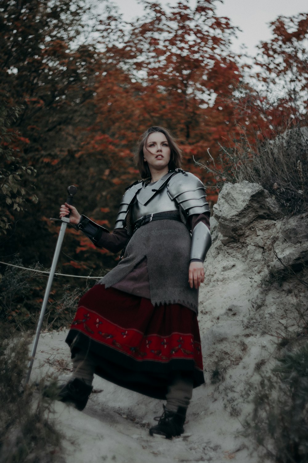 a woman dressed in medieval clothing is walking up a hill