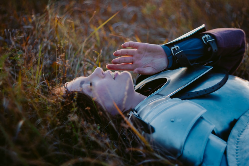 a person laying in the grass with their hand on their face