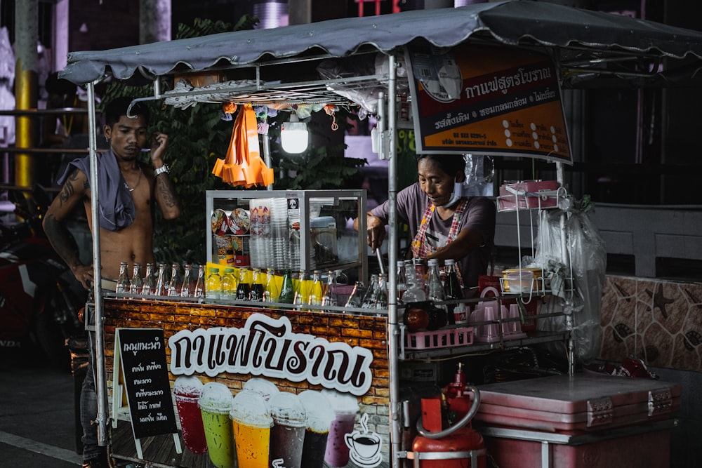 a man standing behind a food cart selling drinks
