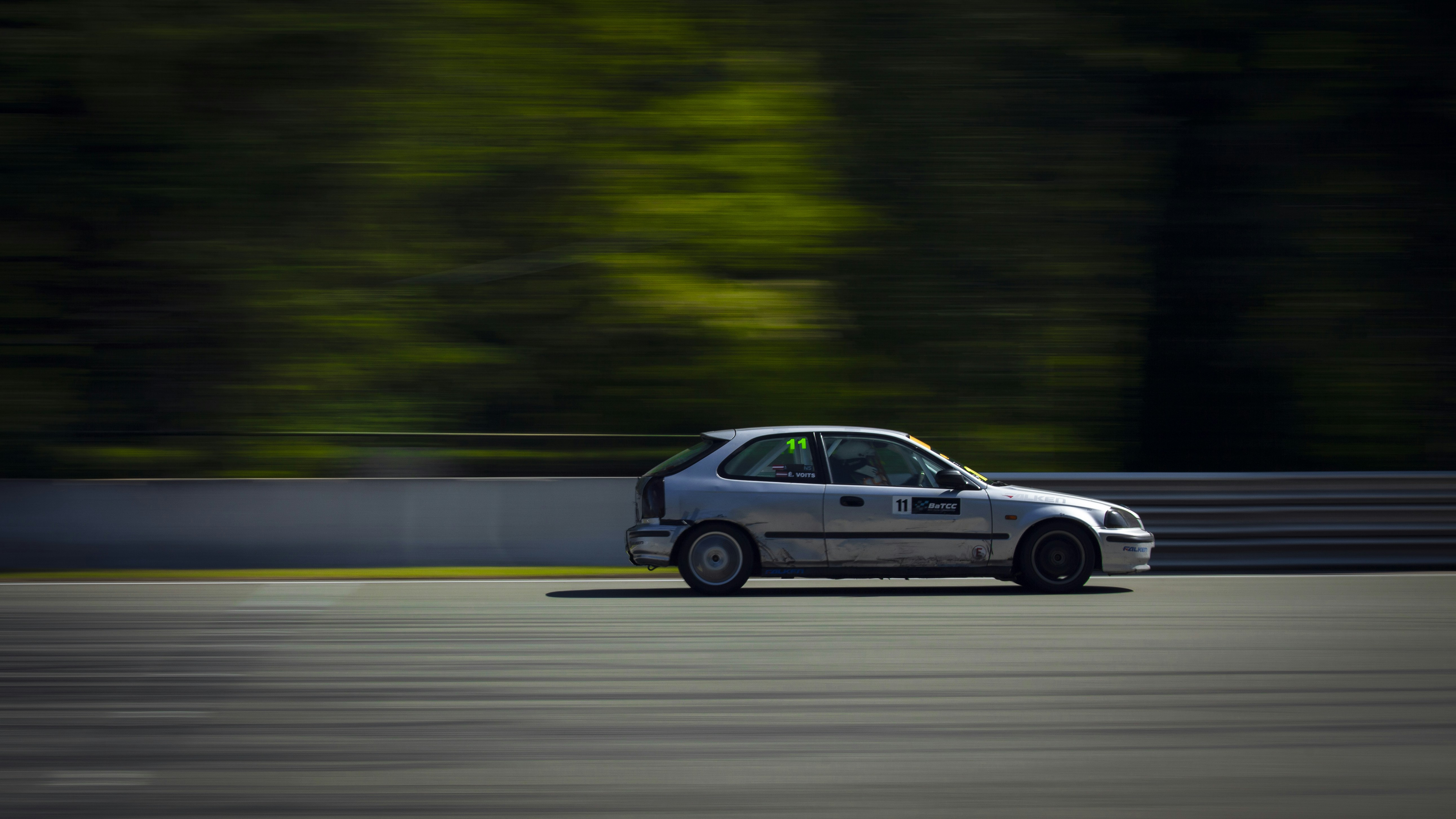 a car driving down a race track with trees in the background