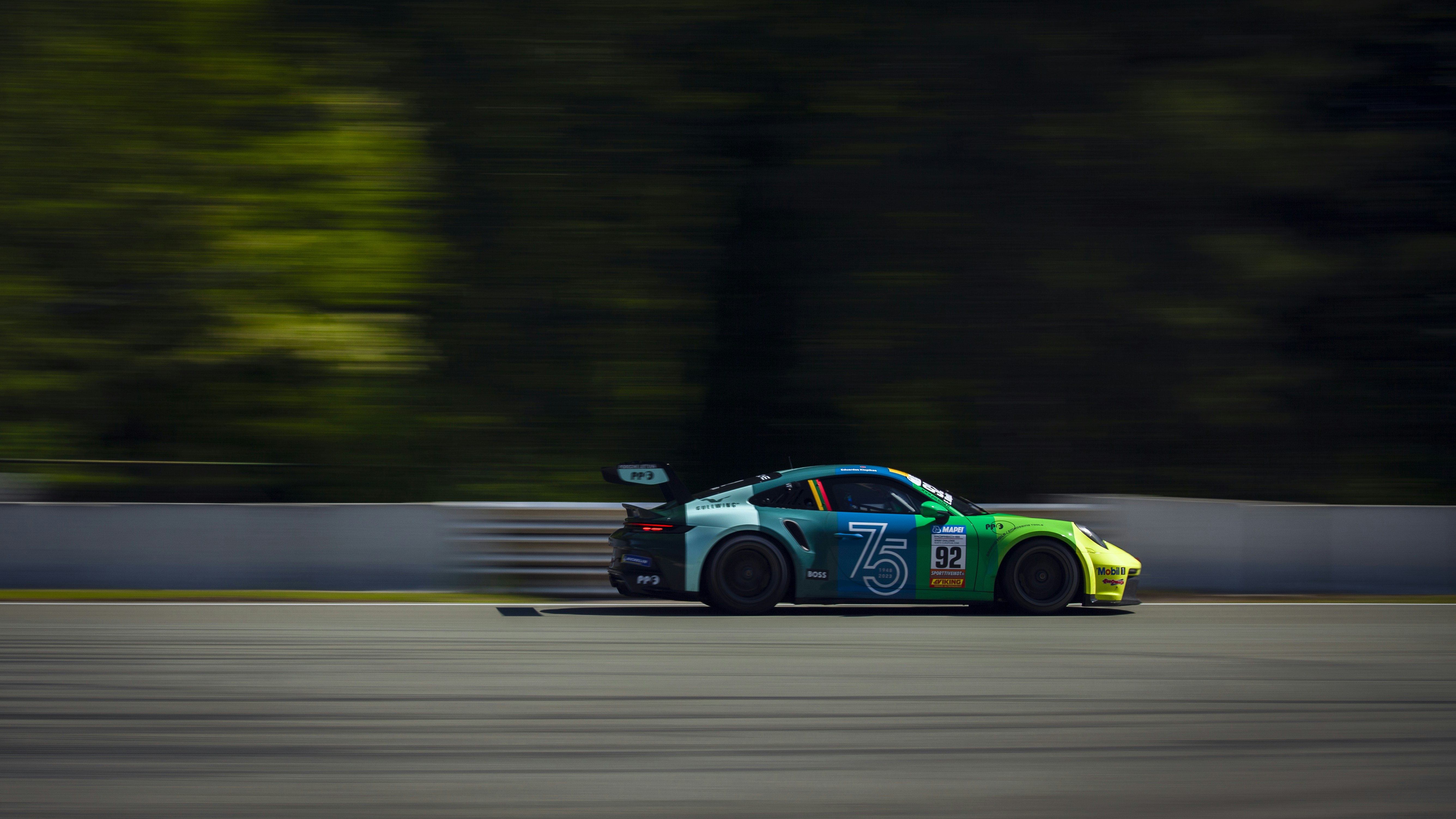 A car driving down a race track with trees in the background photo ...